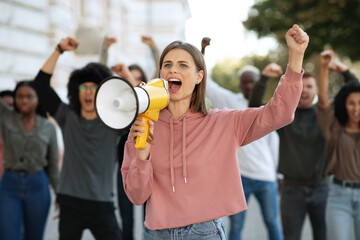 Young woman with megaphone leading group of protestors