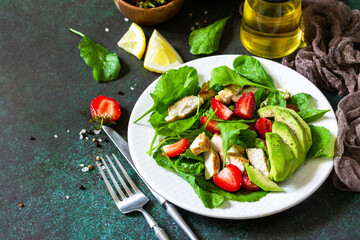 Healthy food, diet lunch menu concept, ketogenic diet and paleodiet. Summer salad with strawberries, grilled chicken and avocado on a stone table. Copy space.