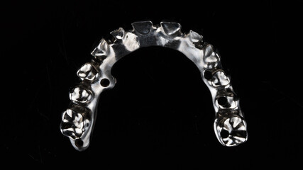minimalism photo of a titanium dental beam of the upper jaw prosthesis on a black background, top view © Dental Pro Content