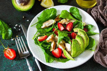 Healthy food, diet lunch menu concept, ketogenic diet and paleodiet. Summer salad with strawberries, grilled chicken and avocado on a stone table.