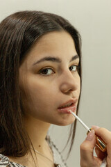 beautiful brunette paints her lips with gloss in her bathroom