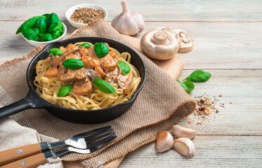 Pasta with mushroom sauce and basil on a light background. Side view with copy space.