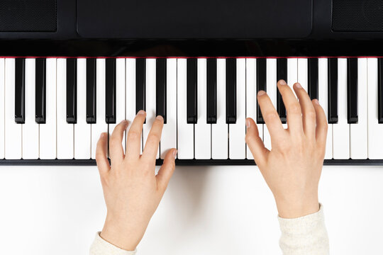 Kid hands learning to play on the piano. Top view