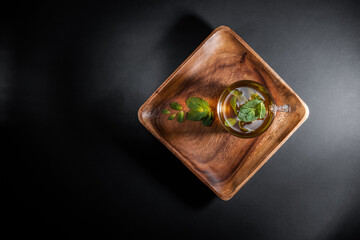 Mint tea leaves in a cup on wooden saucer, isolated on gray black background