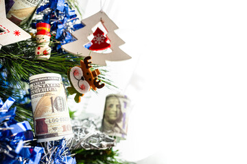 Detail of christmas tree with decorations and dollar bills wishing to earn money in the new year eve, with blank copy space.