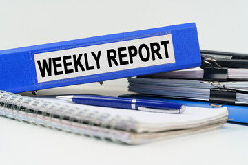 Naklejka premium On the table are a notebook, a pen, documents and a folder with the inscription - WEEKLY REPORT