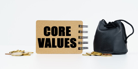 On a white background lies a bag with money, coins and a notebook with the inscription - CORE VALUES