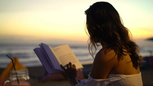 Young woman reading book in cafe at the beach