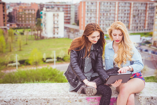 Two young girls using technological devices
