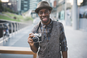 Young black man holding instant camera smiling