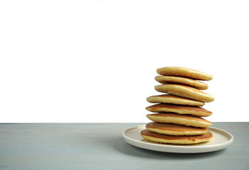 A stack of pancakes on a plate on a gray table with an isolated white top