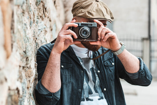 Young hipster man taking a photo with an old, retro camera.