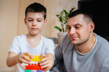Obraz premium A little boy together with his father is played by a constructor and builds a house. Construction of a family home.