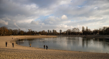 Bundek lake in Zagreb city with flock of birds gathering on the lake surface, observed by the people passing by