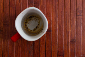 Red cup of coffee with coffee grounds on wooden background