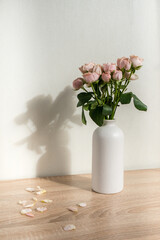 Modern ceramic vase with roses. White wall background. Scandinavian interior. 