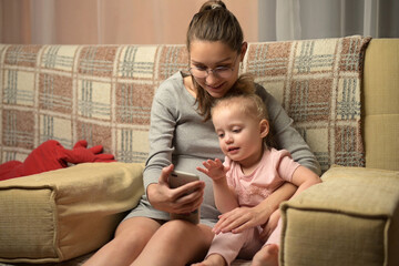 A young pregnant woman and her little daughter make video calls to relatives