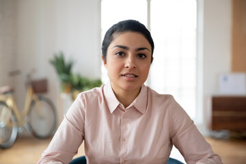 Close up screen view portrait of young Indian female employee look at camera have webcam digital communication in office. Millennial mixed race woman talk speak on video call with client.