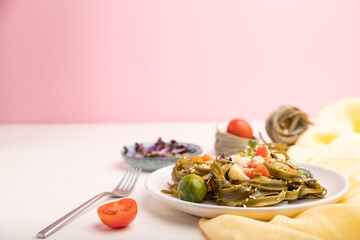 Tagliatelle green spinach pasta with tomato, pea and microgreen sprouts on a white and pink background. Side view, selective focus, copy space.