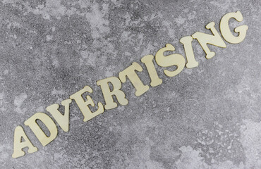 Advertising concept with diagonal word in alphabet letters on a grey textured background viewed as a flat lay still life with copyspace