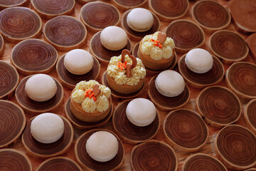 white delicate lowly macaroons on a wooden background. The pastel tone of the cream inside the French cookies