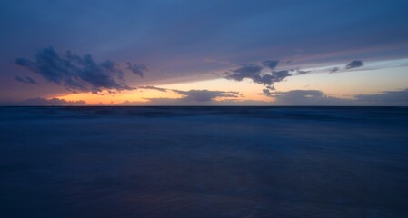 Baltic sea at sunset. Dramatic twilight sky, blue and pink glowing clouds, golden sunlight. Waves, splashing water. Picturesque scenery, seascape, cloudscape, nature. Panoramic view, long exposure
