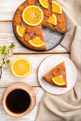 Orange cake and a cup of coffee on a white wooden background. Top view, close up.
