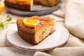 Orange cake and a cup of coffee on a white wooden background. Side view, selective focus.