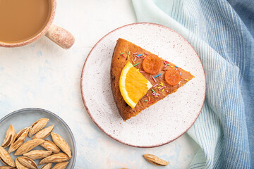 Orange cake with almonds and a cup of coffee on a white concrete background. Top view, close up.