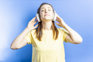 Smiling beautiful young woman with closed eyes enjoying listening to music with sound canceling music headphones. music concept