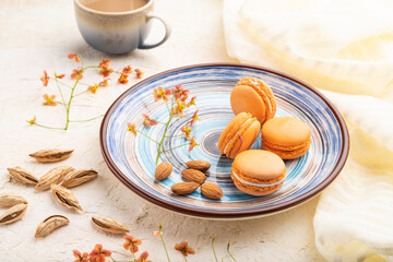 Orange macarons or macaroons cakes with cup of coffee on a white concrete background. Side view.