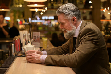 An adult man is bored in the evening in a pair and sips whiskey