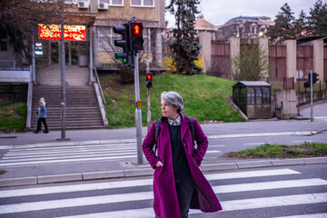 A woman in a purple coat crosses the intersection at a red light