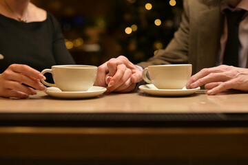 Hands of two people and cups of tea at the bar. Close-up of the hands of two