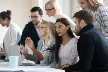 Multiethnic colleagues work in groups brainstorm using computers engaged in team discussion at office meeting. Diverse multiracial employees cooperate consider business ideas. Teamwork concept.