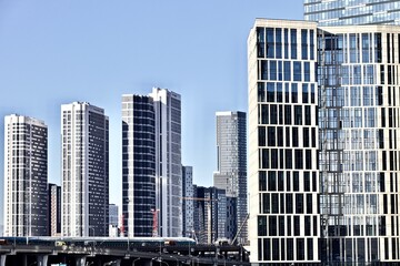 Residential skyscrapers against bright clear blue sky. Cityscape view in bright sunny day. Modern residential city district. Modern urban architecture in city downtown. New residential buildings.