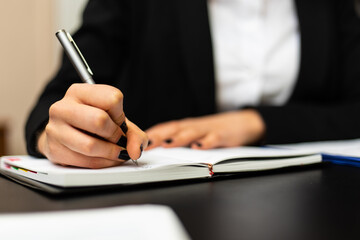 Closeup of a female manager writing and taking notes on a sheet in her office