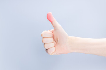 hand finger pain creative concept. accident injury conceptual. person showing red thumbs up over grey background