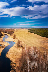 Forest landscape with sky, field and river. Spring sunny day, wild European nature. Beautiful sky. Top view, aerial photography.