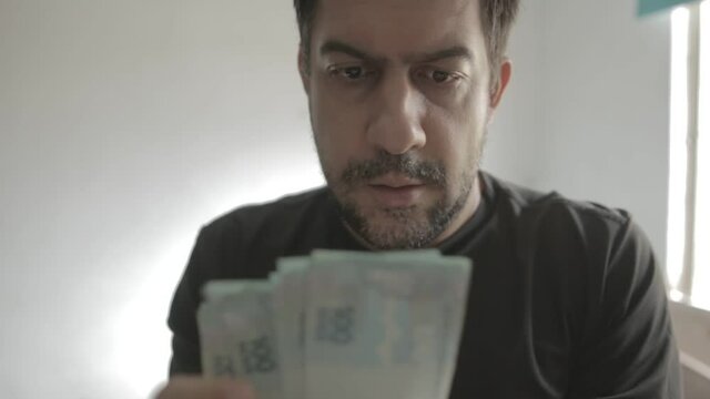 A close up shot of a man holding and counting money banknotes of Brazilian Real