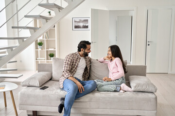 Happy young indian father with teenage child daughter having fun enjoying talking spending time at...