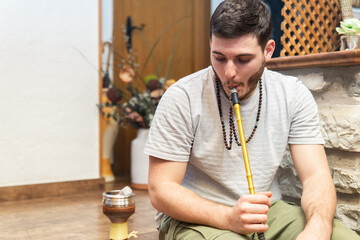 Young handsome guy smoking hookah alone closeup. Hookah and sparks from coals. Shisha, spark, hookah sparks. Young man smokes a fragrant oriental hookah.