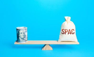 Bundle of dollars and a bag of SPAC on scales. The concept of attracting investors' money to fund...