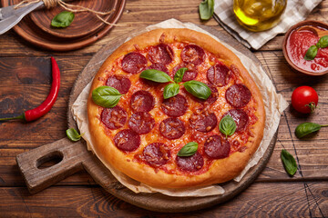 Pepperoni pizza. American style homemade pizza with salami, mozzarella cheese and tomato sauce. Freshly baked and served with basil leafs.