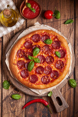 Pepperoni pizza. American style homemade pizza with salami, mozzarella cheese and tomato sauce. Freshly baked and served with basil leafs.