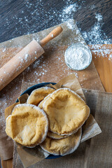 Stack of homemade, fluffy, pita bread. Freshly baked gluten-free pita bread on a rustic cloth, hot from the oven. Round flatbread that can be stuffed with food. Rolling pin and flour in the background