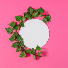 Creative spring or summer layout made of natural green branch and round frame layout for copy space. Flat lay. Pink background.