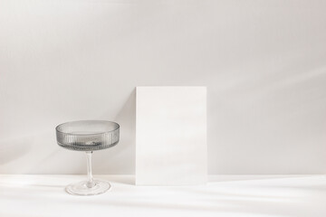 Modern summer still life scene. Grey chanpagne textured glass with drink in sunlight with long...