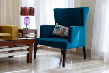 Teal soft vintage armchair. Turquoise velvet armchair next to the window in the living room