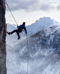 Epic Adventurous Extreme Sport Composite of Rock Climbing Man Rappelling from a Cliff. Mountain Landscape Background from British Columbia, Canada. Concept: Explore, Hike, Adventure, Lifestyle
